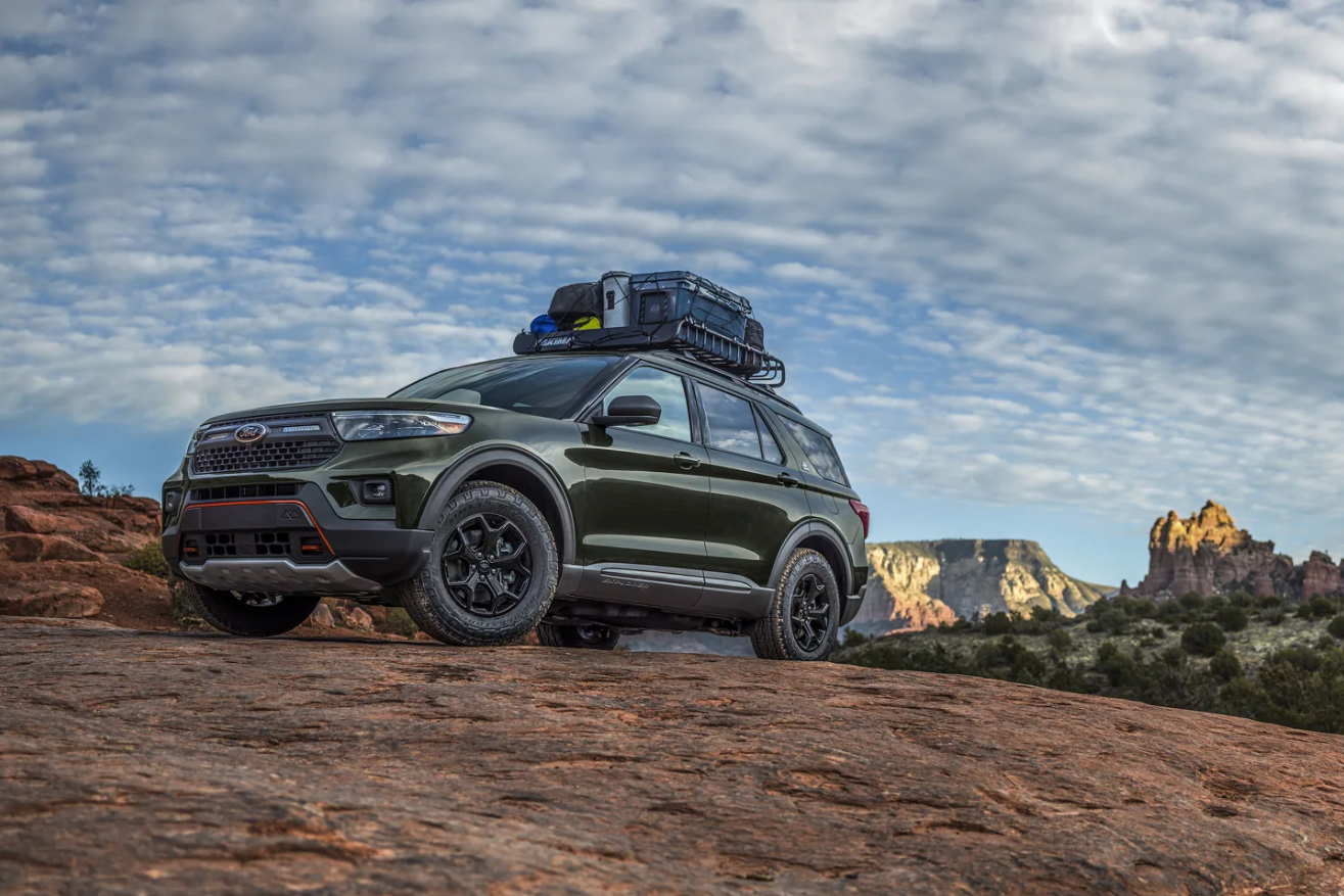 A dark green 2023 Ford Explorer with equipment loaded on its roof sits parked on a mountain road